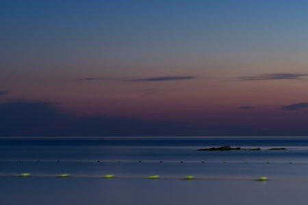 Long exposure. The sea against the twilight sky. Late sunset. The stone protrudes from the water....