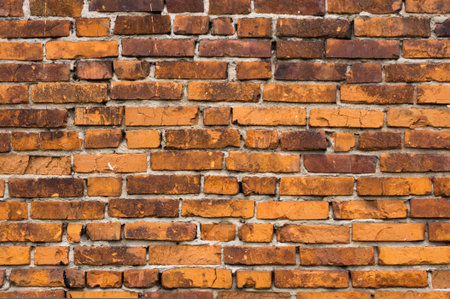 Background of old brick wall. The old orange-brown cracked brick, uneven rows
