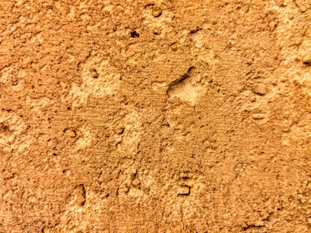 Texture of old rustic wall covered with yellow stucco. Abstract background for design.の写真素材