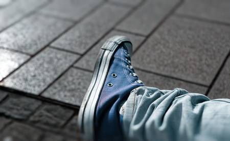 Sneaker shoes with blurred picture border and cobblestones in the backgroundの写真素材