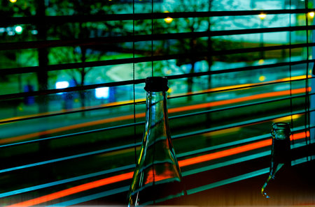 Bottles in front of a venetian blind in the city at night with blue cold colors with long exposure...