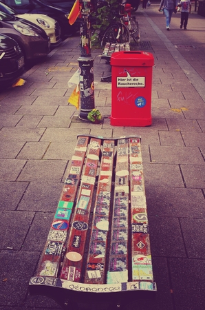 Park bench in the Hamburg Schanzenviertel opposite the red flora with many lifters and red trash canのeditorial素材