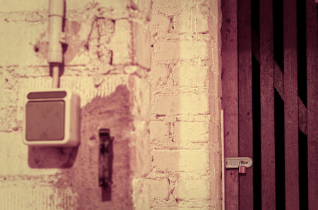 Cellar with a padlock and a cellar door in a tenement with a light switch in violet optics