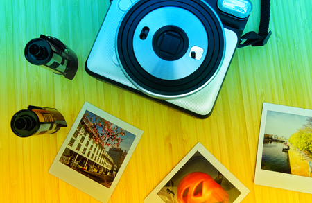Instant camera in white with exposed instant films and drotty headphones on a bamboo table  and yellow greenの写真素材