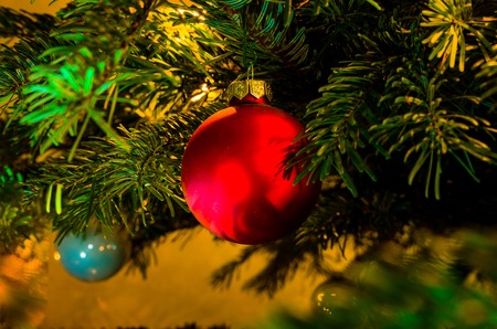 Christmas bauble on a Christmas tree and glowing lightsの写真素材