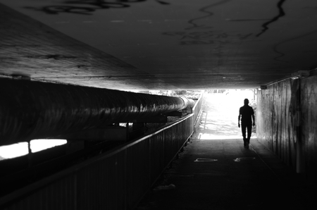Walkers in a tunnel in black with a view of the bright tunnel exitの写真素材