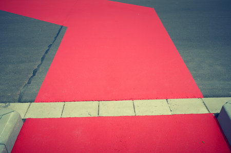 Red marker of a bicycle lane with a roadの写真素材