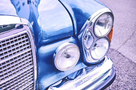 Old vintage car in blue with grille and lamps with lots of chrome