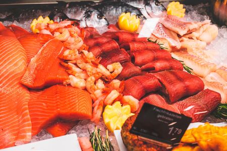 Fish fillets in a fish counter of a delicatessen with salmon, rollmops and inscription in german Fischfrikadellen und english Fish Meatballsの写真素材