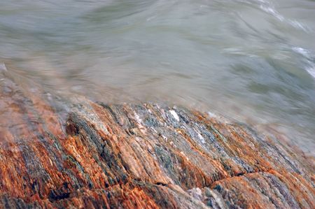 A glacial stream flows over multicolored bedrockの写真素材