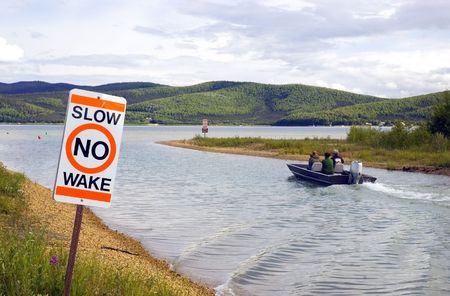 A boat defies the No Wake sign at a lakeの写真素材