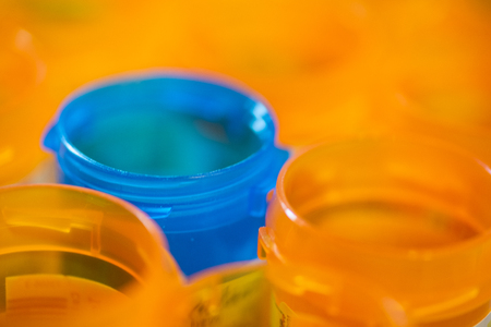 A blue pill bottle surrounded by orange pill bottles.の写真素材