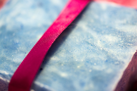 Bar of blue hand crafted soap with a red ribbon.の写真素材