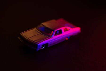 A toy car under red and blue lights, dark background.の写真素材
