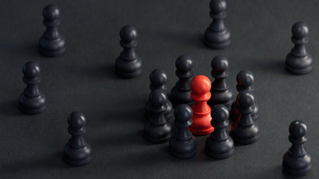 Leadership concept. Red leader standing out from the crowd of black pawns.の写真素材