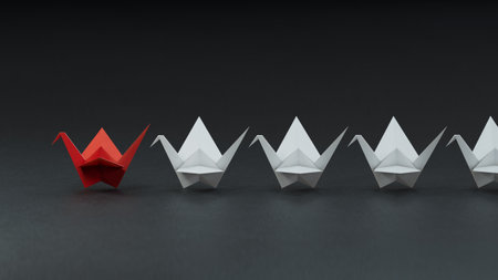 Leadership concept with red paper ship leading among white ones on black backgroundの写真素材