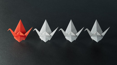 Leadership concept. Paper origami crane leading the group of white origami ships on black backgroundの写真素材
