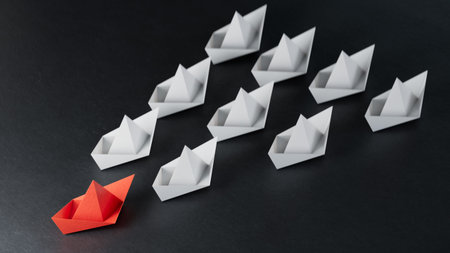 Different business concept.new ideas.paper art style.Leadership concept with red paper ship leading among white boats.3D rendering on black background.の写真素材