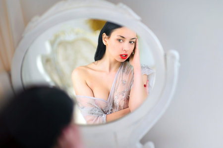 Young sexy woman at mirror in bedroom.の写真素材