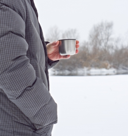 cup with hot tea in a hike when it is snowingの写真素材