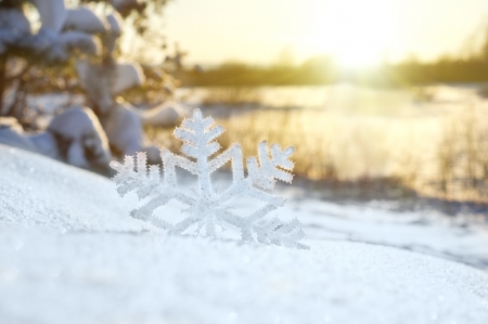 Decorative snowflake on snow at sunsetの写真素材