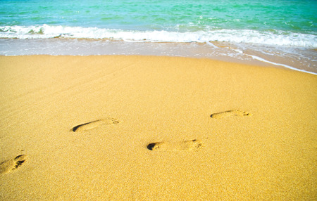 Footprints on the beach sand by the seaの写真素材