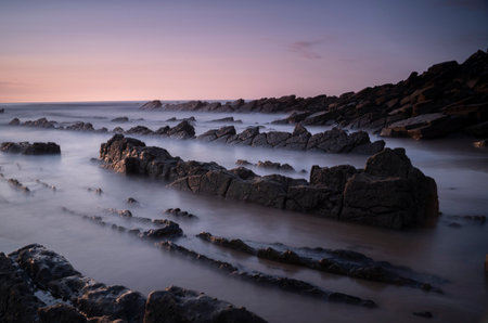 rocks on the beach sand under a red sunset lightの写真素材