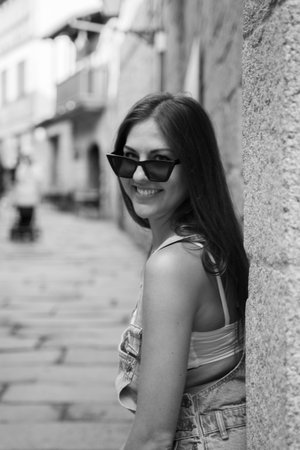 beautiful caucasic girl with sunglasses looking to camera and smiling in the streets of Spain