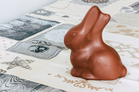 A milk chocolate rabbit, a gift for Easter, on a tablecloth decorated with drawings.の写真素材