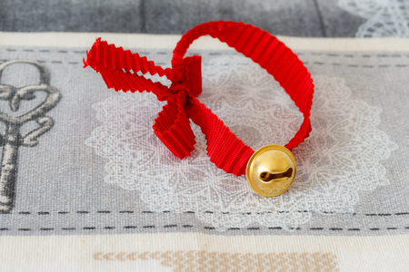 A yellow rattle and a red ribbon on a table cloth.の写真素材