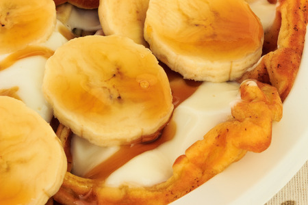 Morning breakfast with waffle, typical Belgian food, stuffed with banana, white yogurt and maple syrup.の写真素材