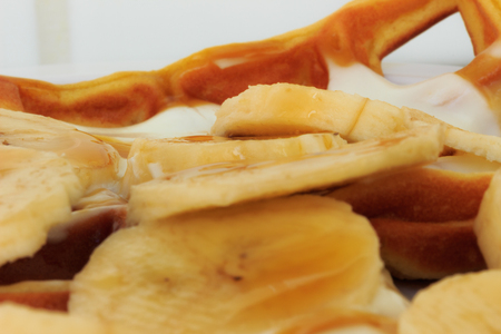 Morning breakfast with waffle, typical Belgian food, stuffed with banana, white yogurt and maple syrup.の写真素材