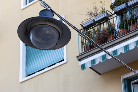 Old lamp suspended from above on the background of buildings.の写真素材