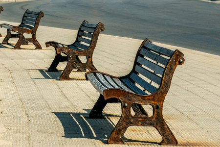 Walk along the seafront of Bari during the afternoon. Old benches, made of wood and iron, on the street.の写真素材