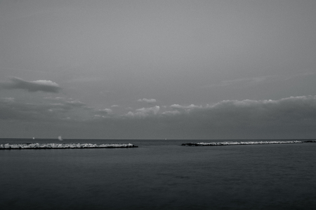 An afternoon on the seafront of the city of Bari, in southern Italy. The panorama of the sea horizon and some sailboats under a cloudy sky.の写真素材