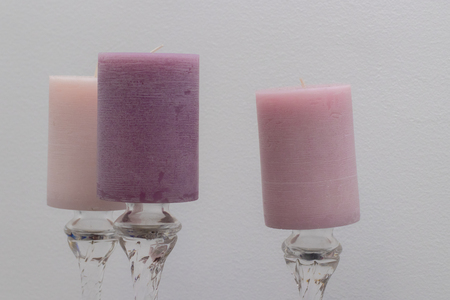 Three scented candles on crystal pedestals on the background of a white bedroom wall.の写真素材