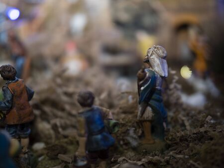 Christmas holidays at home. A christmas nativity scene with lights and small wooden statues illuminates the living room during the evening.の写真素材