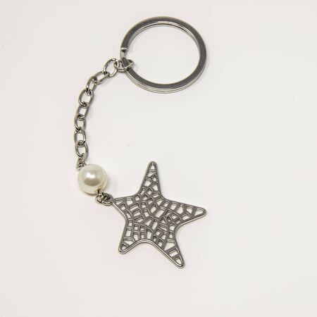 Useful items for the home. A small metal keyring with a starfish-shaped pendant and a small white pearl.の写真素材