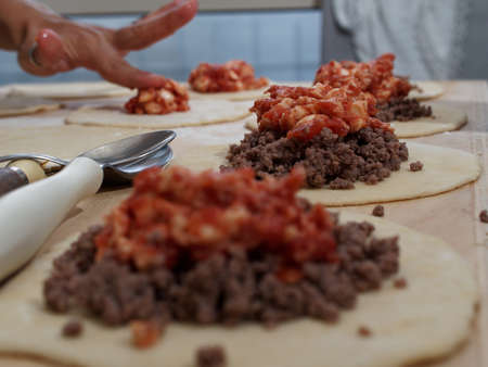 Preparations for a panzerotto, a specialty of southern Italian cuisine. Minced meat, mozzarella and tomato poured as a filling on the dough.の写真素材