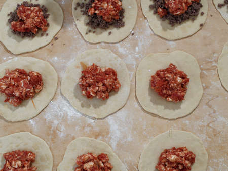 Preparations for a panzerotto, a specialty of southern Italian cuisine. Minced meat, mozzarella and tomato poured as a filling on the dough.の写真素材