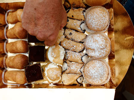 One of the most anticipated moments during a lunch in Italy. At the end of the meal, small pastries arrive served on a golden paper tray.の写真素材