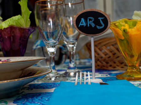 Preparing a dinner for a birthday party with guests in the house. Wooden place cards in the shape of a blackboard with the names written with colored chalk.の写真素材