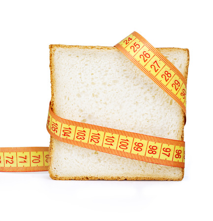 Piece of bread grasped by measuring tape isolated on whiteの写真素材
