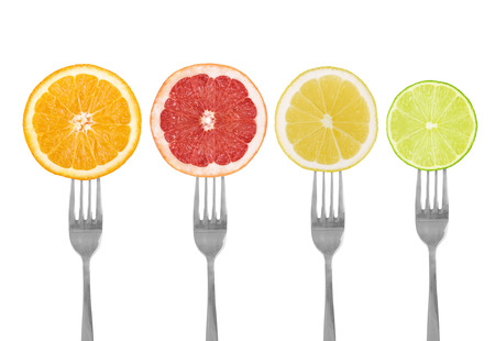 citrus fruit on forks lime, orange, grapefruit, lemon isolated against whiteの写真素材