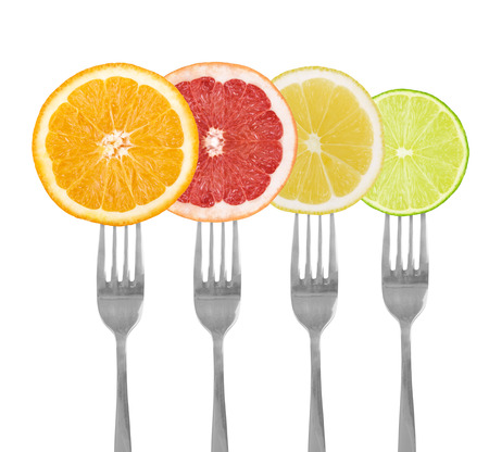 citrus fruit on forks lime, orange, grapefruit, lemon isolated against whiteの写真素材