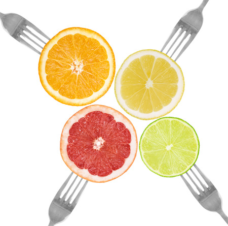 citrus fruit on forks lime, orange, grapefruit, lemon isolated against whiteの写真素材
