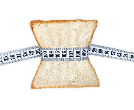 Piece of bread grasped by measuring tape isolated on whiteの写真素材