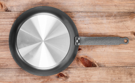 Frying pan on wooden table background. View from aboveの写真素材
