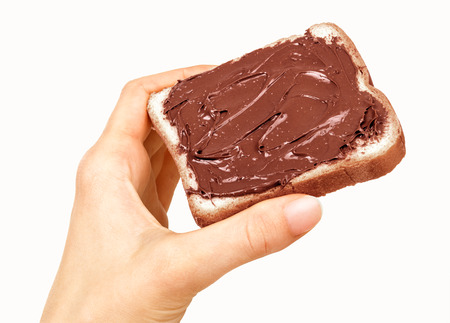 baguette slice spread with nut-choco paste in man hand, isolated on whiteの写真素材