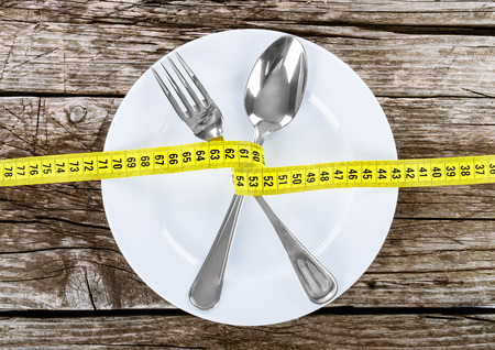 Fork and measuring tape on a thin wooden backgroundの写真素材
